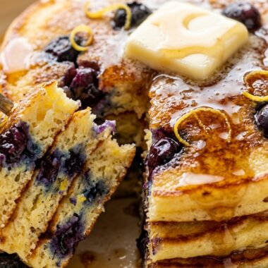 Ultra close-up macro of fluffy lemon ricotta blueberry pancakes with melting butter and maple syrup