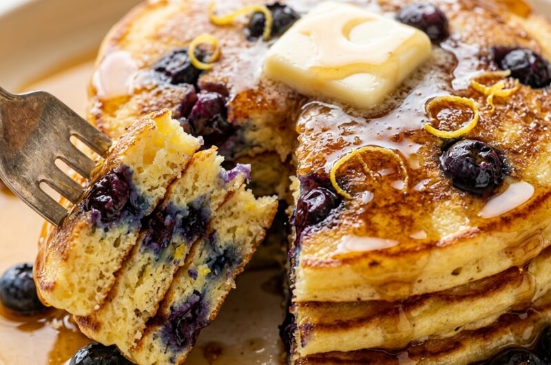 Ultra close-up macro of fluffy lemon ricotta blueberry pancakes with melting butter and maple syrup