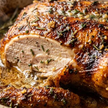 Ultra close-up macro of garlic herb butter roasted whole chicken with crackly mahogany skin and carved juicy breast